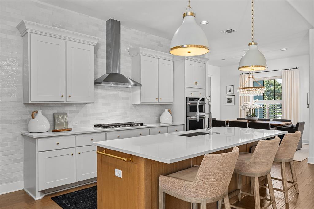 Kitchen with white shaker cabinets, gold pendants, island sink and breakfast nook