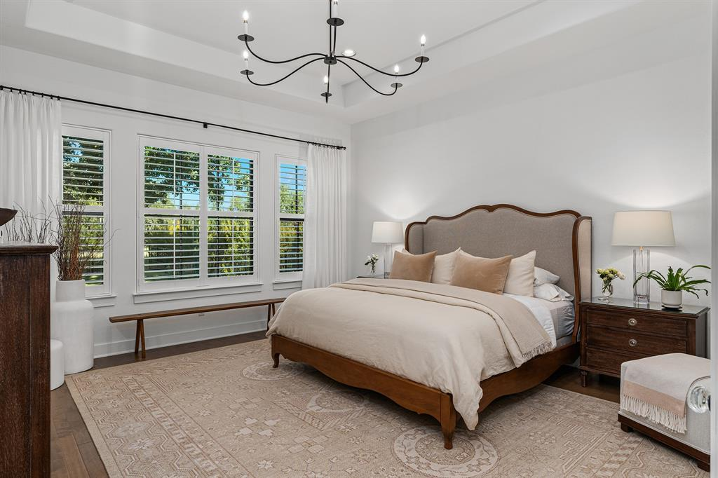 Primary suite with tray ceiling, plantation shutters and garden views