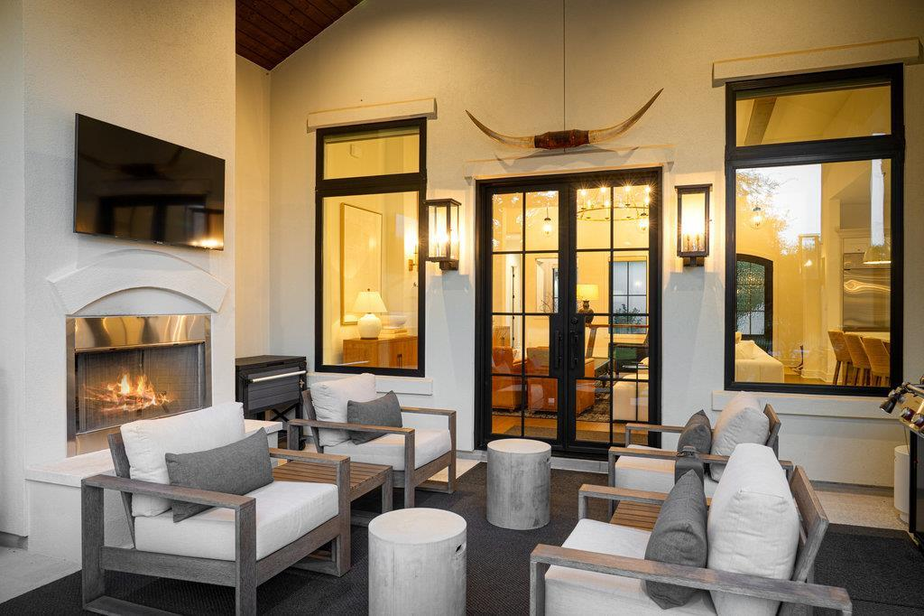 Covered patio with outdoor fireplace, TV, seating area and longhorn mount